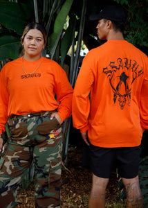 Two people wearing bright orange shirts with a deer design and text, standing outdoors.