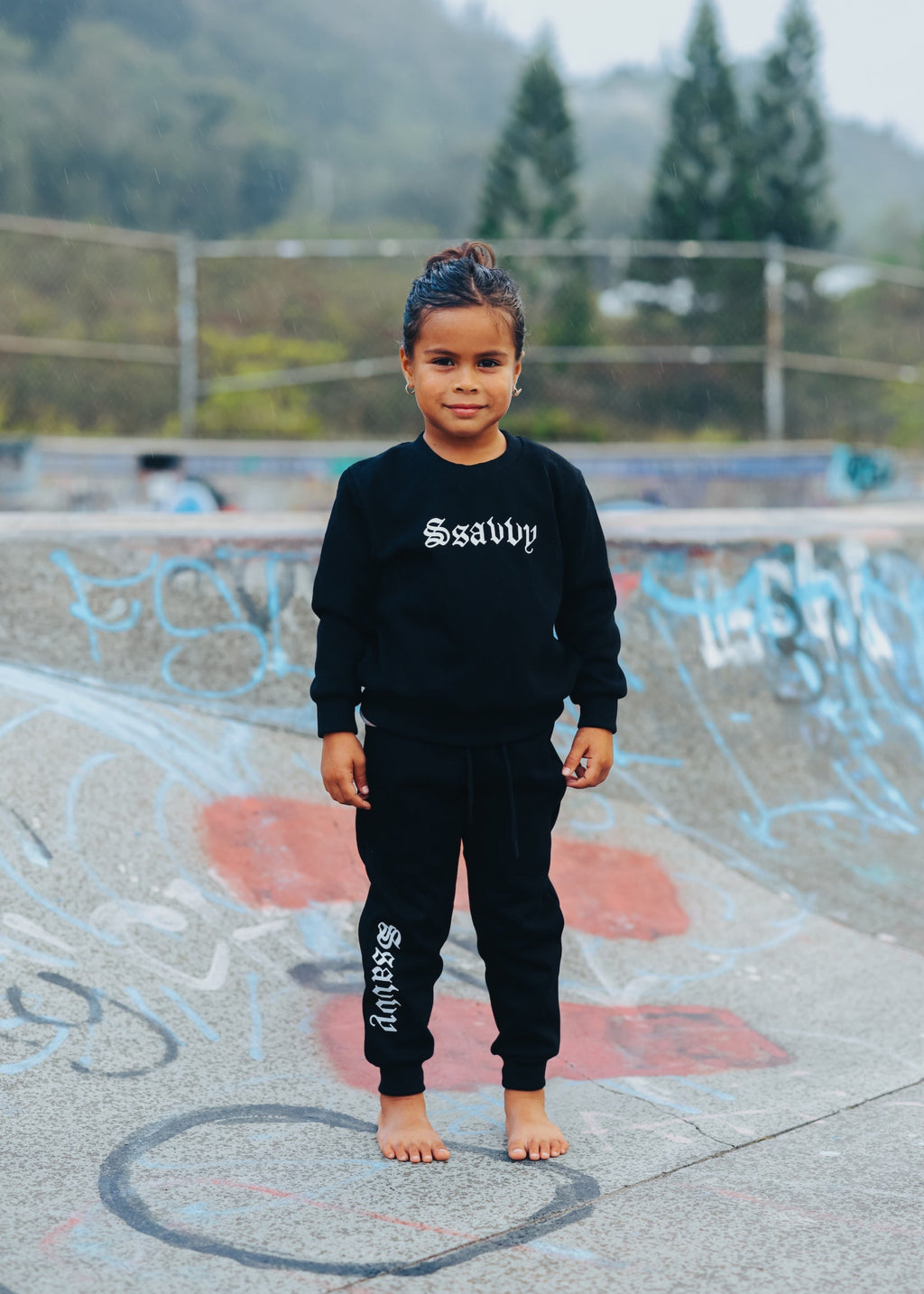 Child wearing a black outfit with visible branding in an outdoor setting