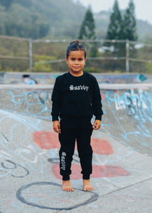 Child wearing a black outfit with visible branding in an outdoor setting