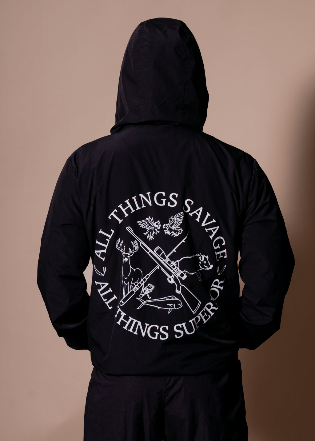 Person wearing a black hoodie with text and graphics on the back against a brown background